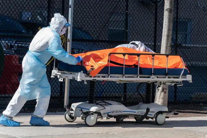 Body of deceased patient in orange bag moved from hospital to refrigerator truck serving as temporary morgue outside of Wyckoff Heights Medical Center in Brooklyn.